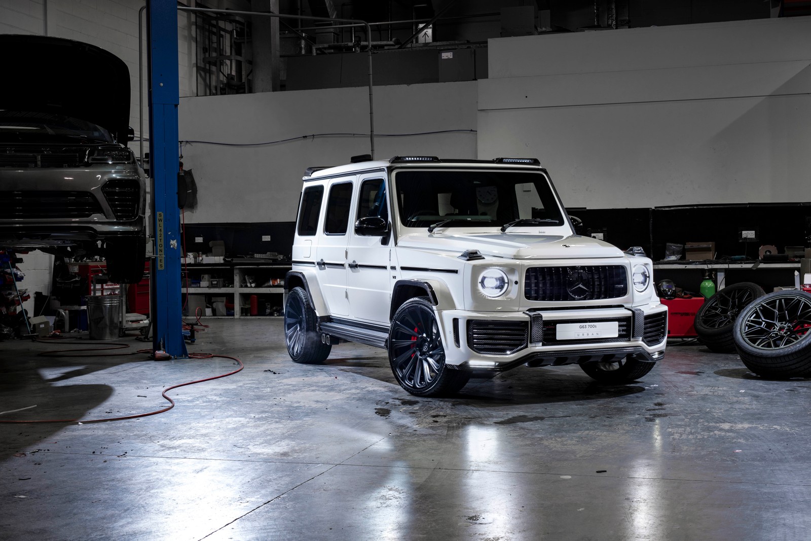 Um mercedes g-class branco estacionado em uma garagem com uma motocicleta (carro, pneu automotivo, roda, pneu, aro)