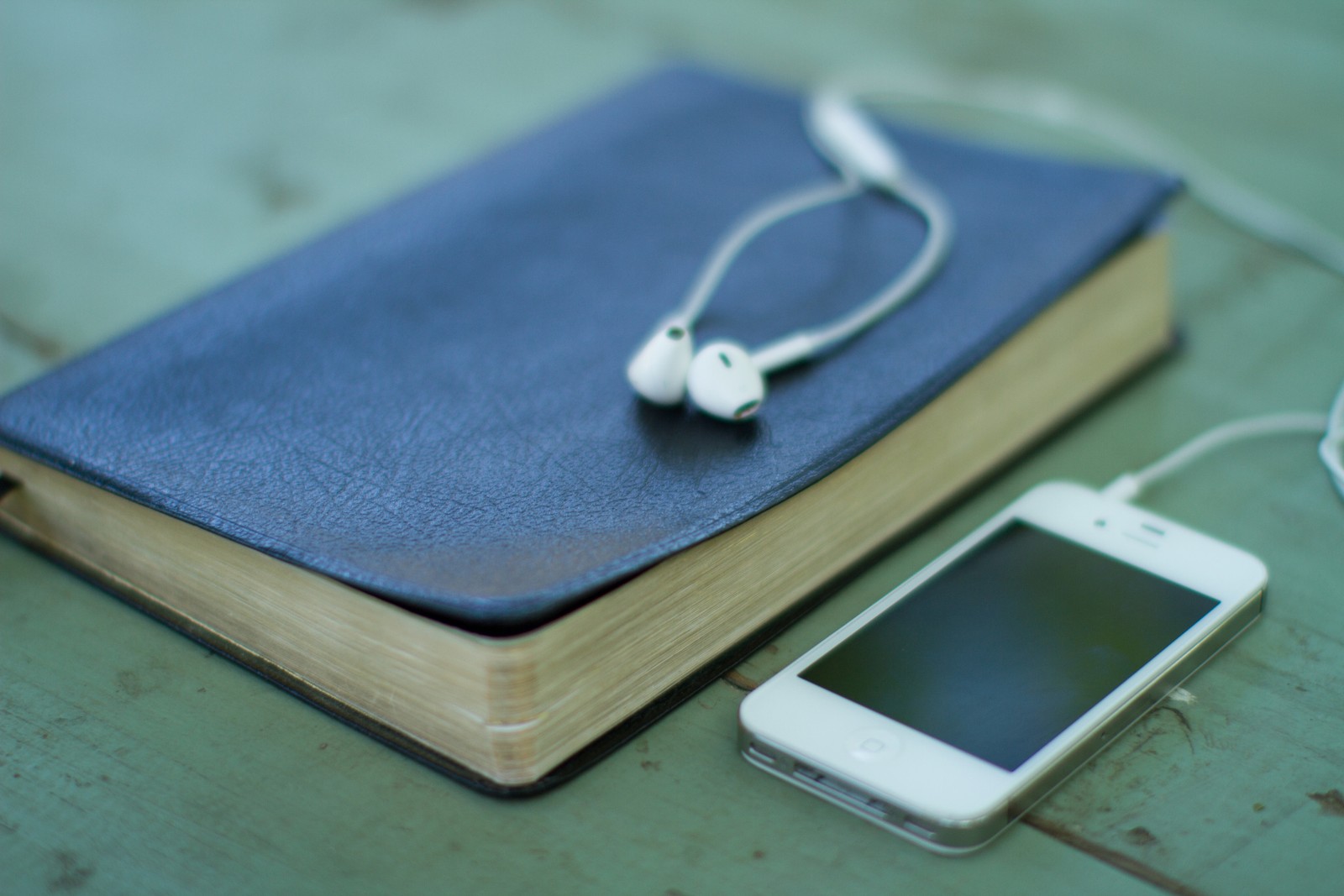 Il y a un téléphone portable et des écouteurs sur un livre (gadget, électronique, technologie, dispositif électronique, accessoire de mode)