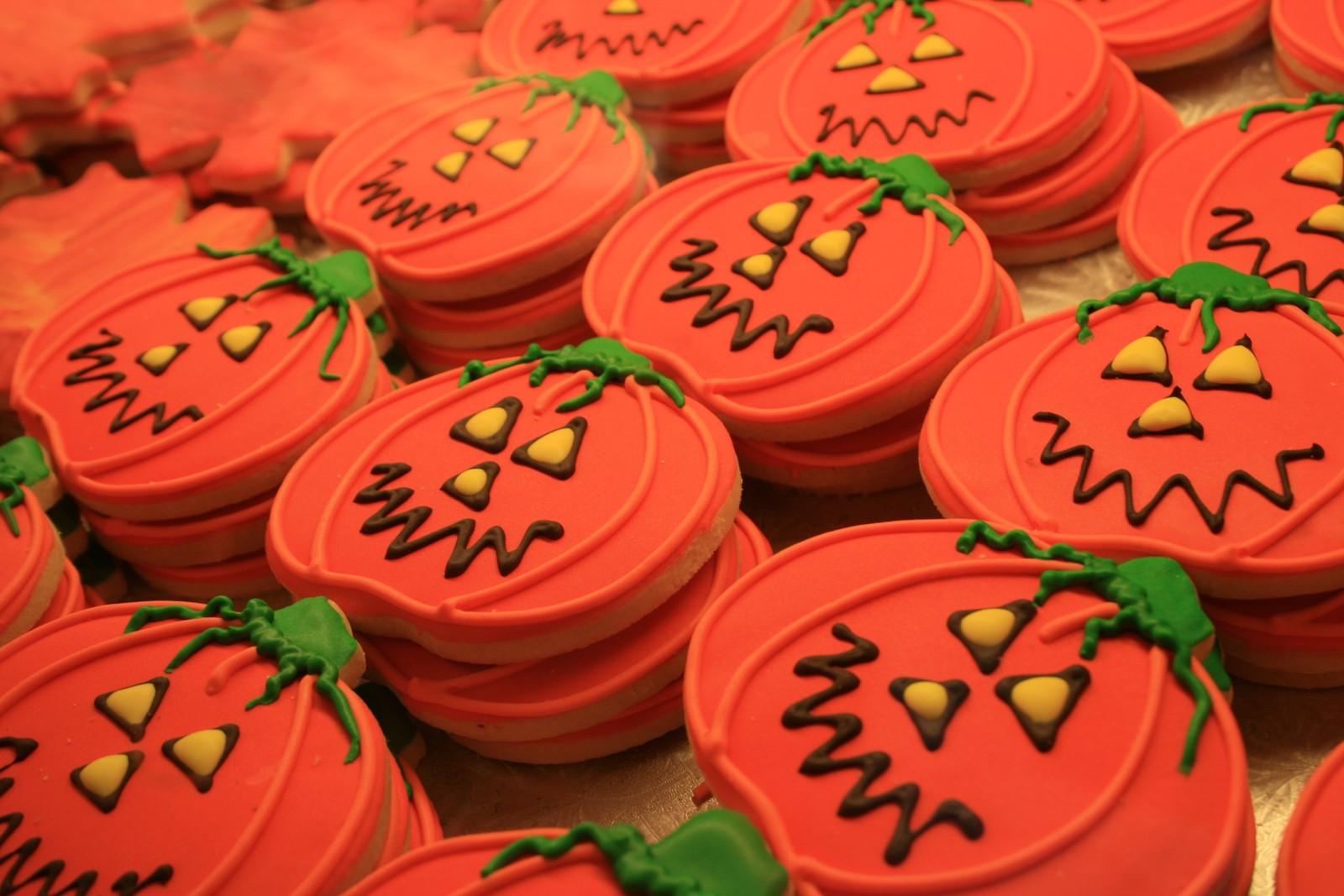 A close up of a tray of decorated cookies with faces on them (icing, sugar cookie, pumpkin, cupcake, dessert)