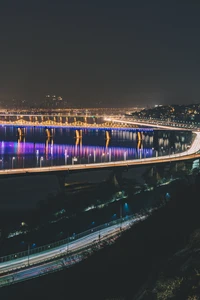 Pont illuminé sur l'eau la nuit dans un paysage urbain