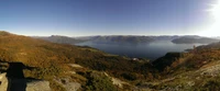 Panoramic View of a Serene Highland Lake Surrounded by Autumn Foliage and Mountains