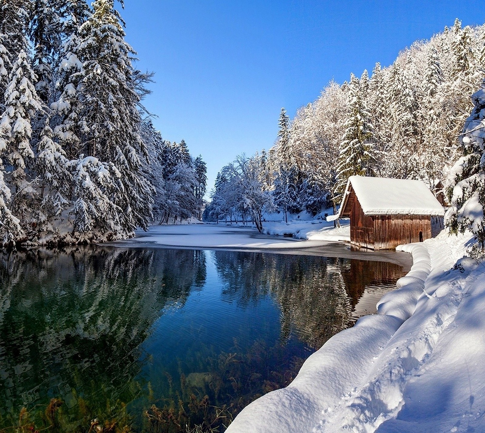 Snowy scene of a cabin by a lake in the woods (frozen, home, lake, landscape, nature)