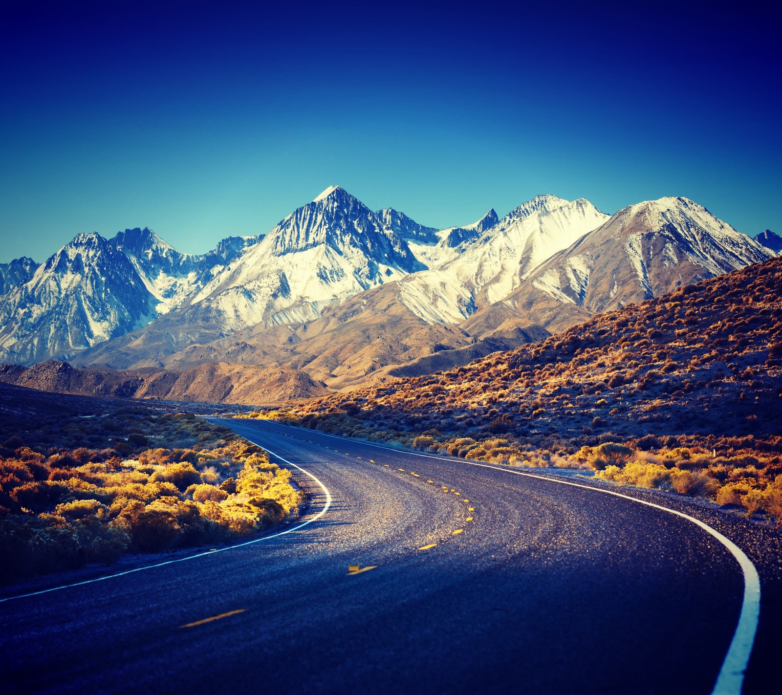 Arafed road with mountains in the background and a blue sky (field, landscape, mountains, nature, road)