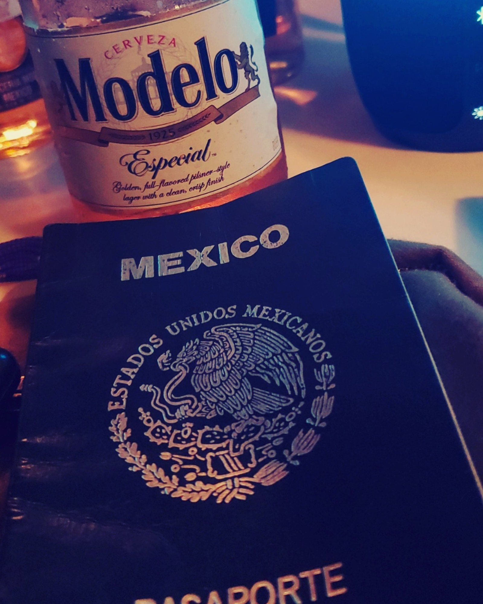 Nahaufnahme eines reisepasses und einer flasche alkohol auf einem tisch (2019, entspannen, corridos, mexiko, modelo)