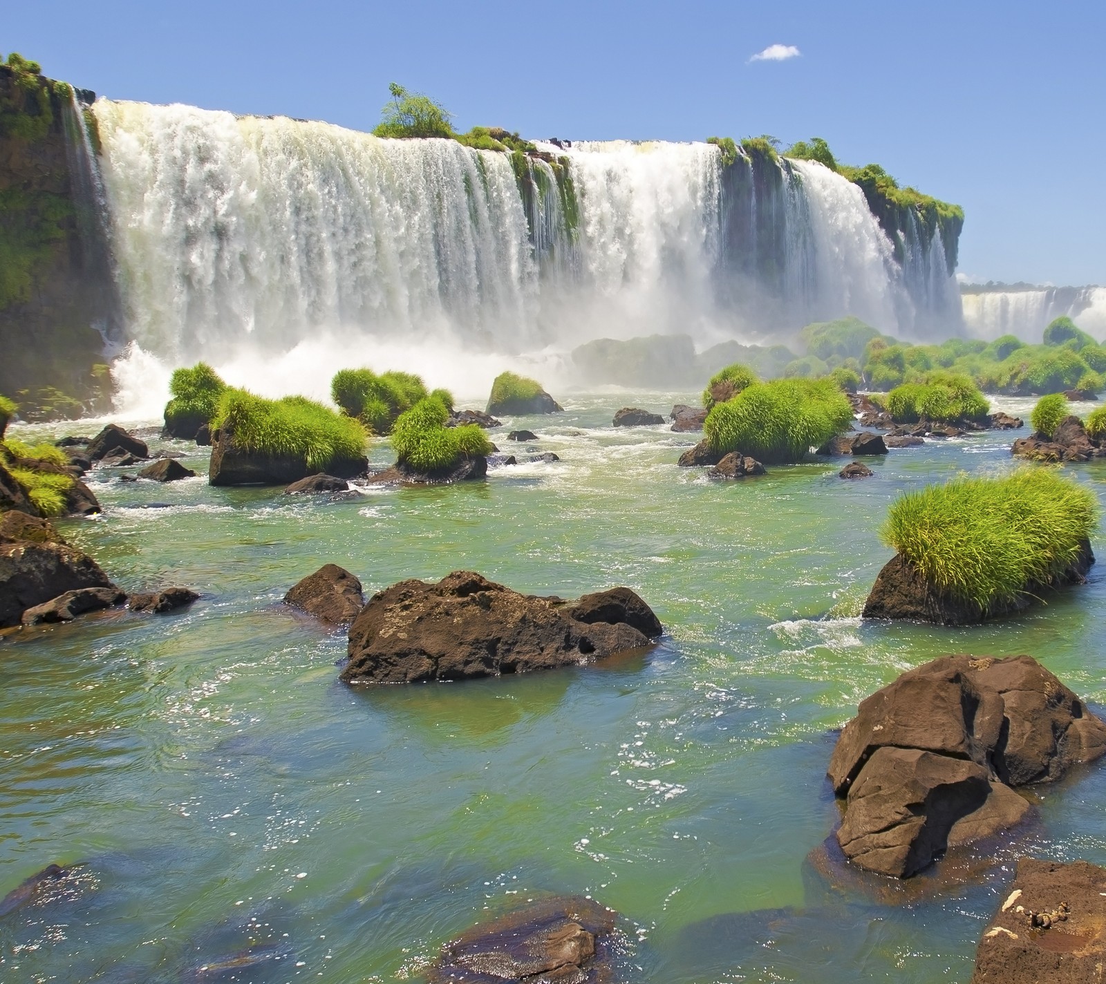 Una cascada com vegetação verde e rochas em primeiro plano (hd, naturaleza, agua, cascada)