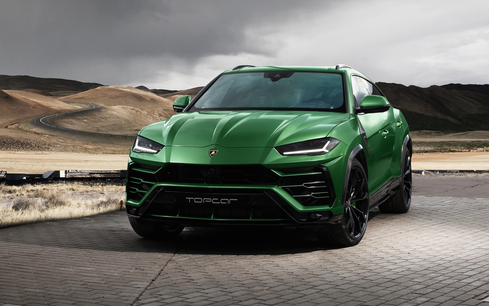 Um suv verde estacionado em uma estrada em frente a uma montanha (sintonizado, lamborghini, urus, topcar, itália)