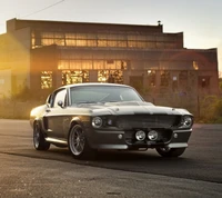 Icônico Ford Mustang GT500 Eleanor de 1967 em um ambiente industrial iluminado pelo sol.