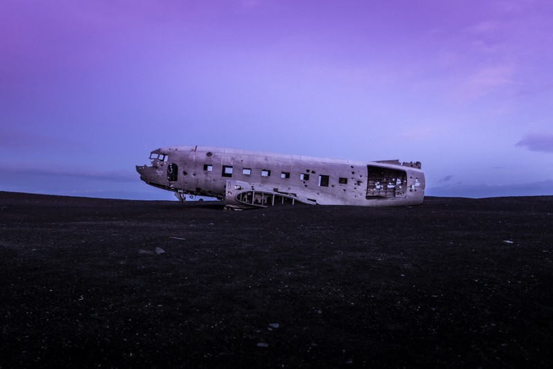 Ein luftbild eines flugzeugs, das auf dem boden in einem feld mit lila himmel sitzt (abgestürztes flugzeug, douglas dc 3, wrecked, verlassen, zweiter weltkrieg)