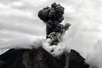 Eruption of Mount Sinabung: Ash Cloud Rising Dramatically Against a Cloudy Sky