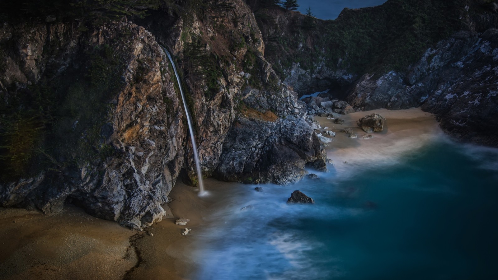 A view of a waterfall flowing over a rocky cliff next to the ocean (waterfall, body of water, water, sea, rock)