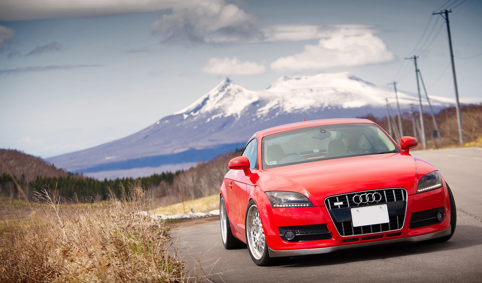 Ein rotes auto, das eine straße mit einem berg im hintergrund entlangfährt (audi tt, audi, auto, kompaktwagen, sportwagen)