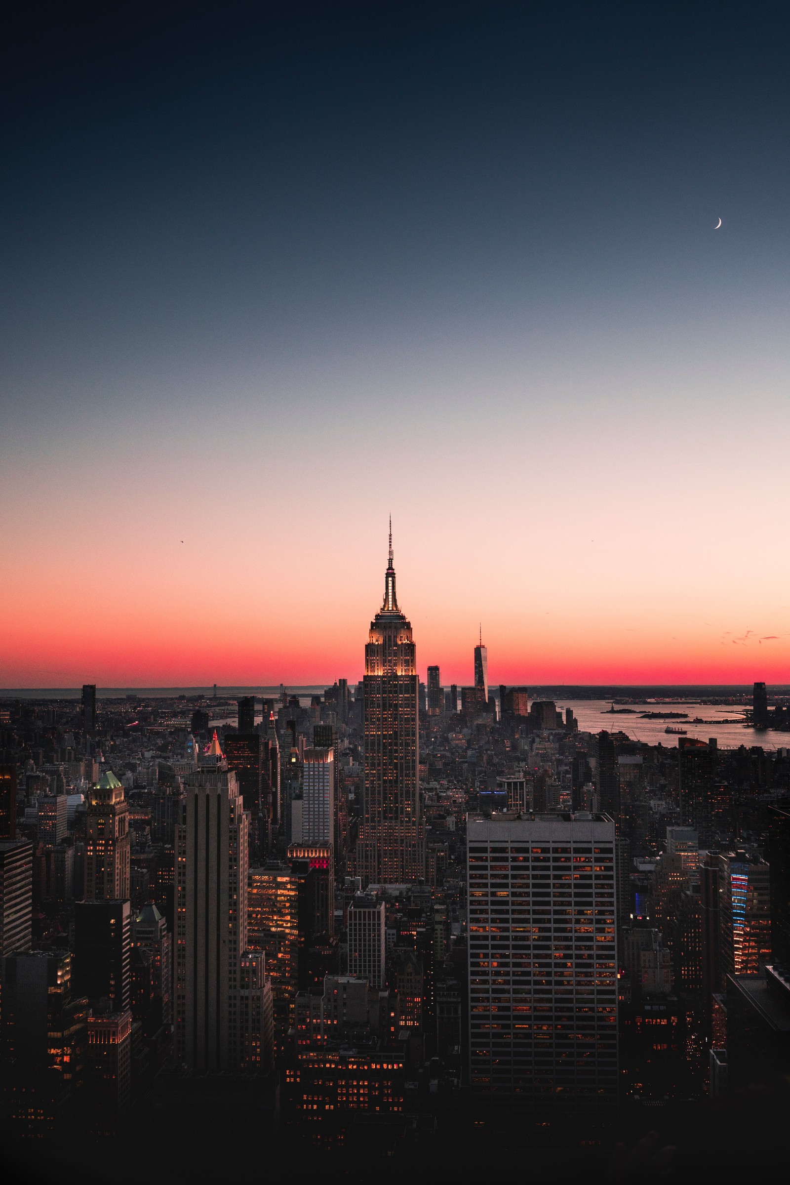 Vista aérea de un horizonte urbano al anochecer con una luna en el cielo (empire state building, rascacielos, nueva york, new york city, atardecer)