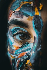 Close-up of a human eye surrounded by vibrant, abstract facial paint, highlighting beauty and artistry against a dark backdrop.