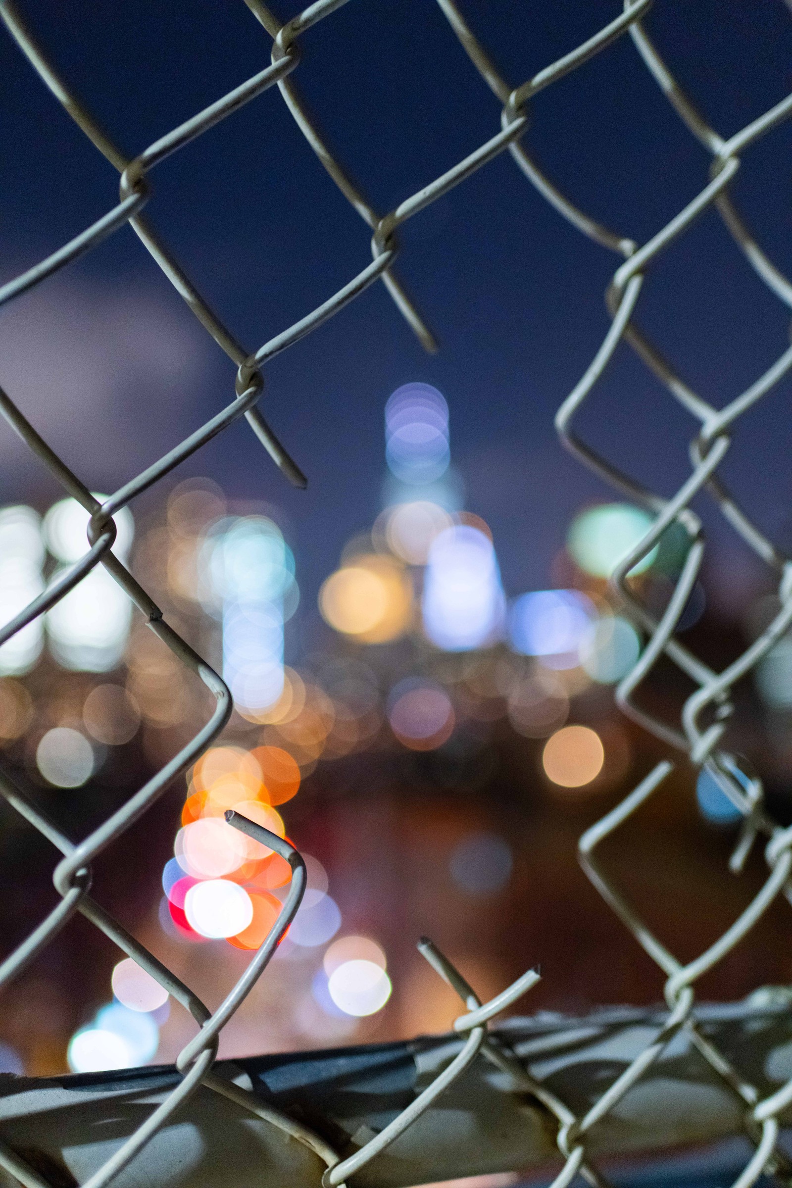 Vue d'une ville derrière une clôture en chaîne (bokeh, clôture, motif, clôture en fil métallique, ville)