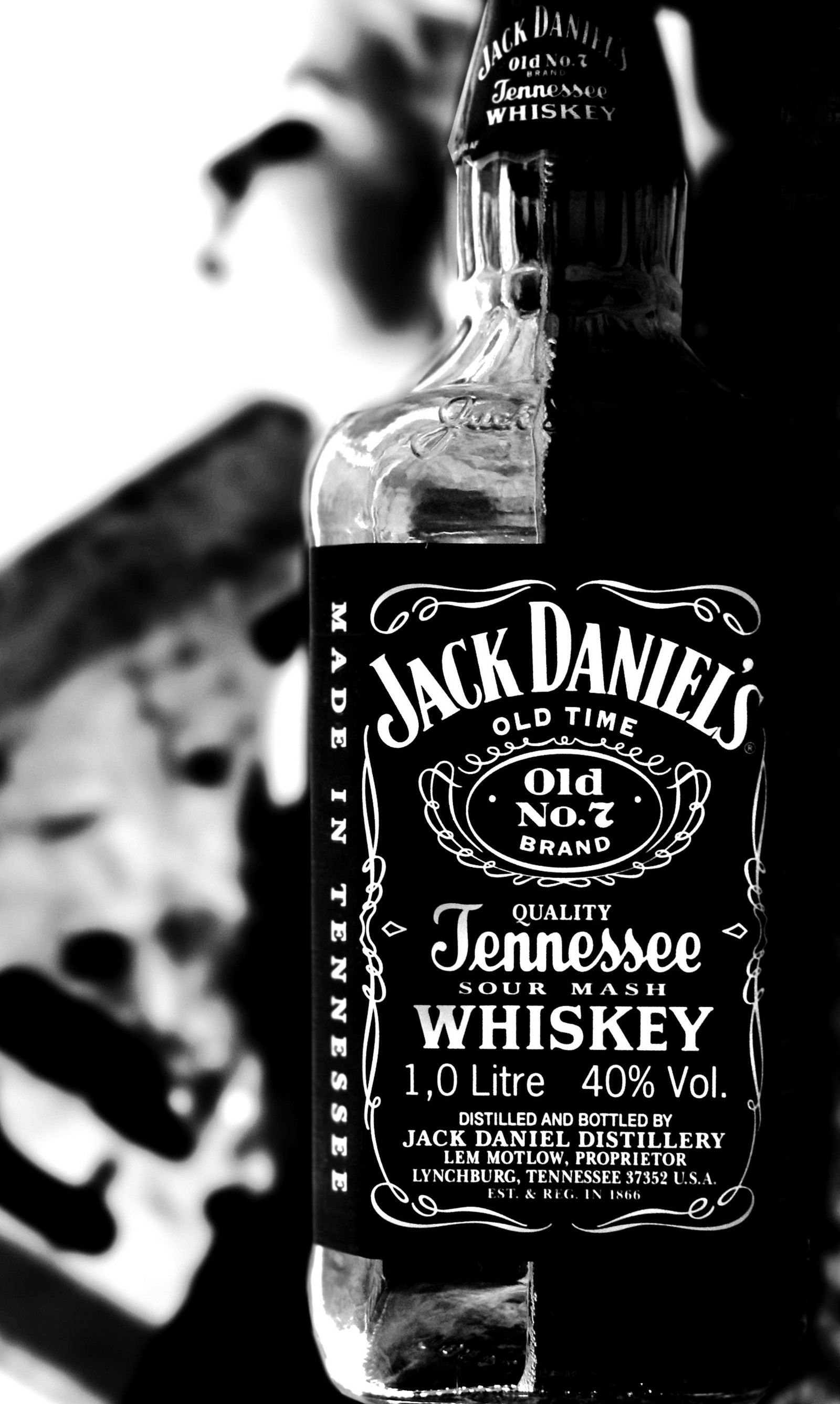 Eine nahaufnahme einer flasche jack daniels whiskey auf einem tisch. (alkohol, schwarz weiß, getränk, droge, whiskey)