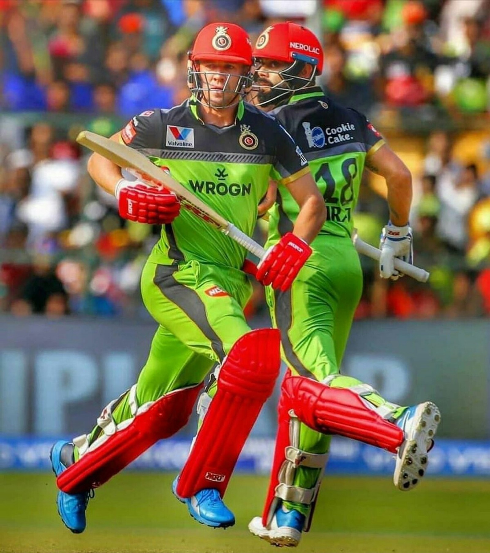 Deux hommes en uniforme vert et rouge jouant à un jeu de cricket (ab deviliars, virat kohli)