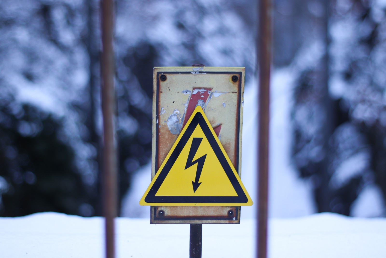 There is a yellow sign with a lightning bolt on it (winter, yellow, snow, sign, signage)