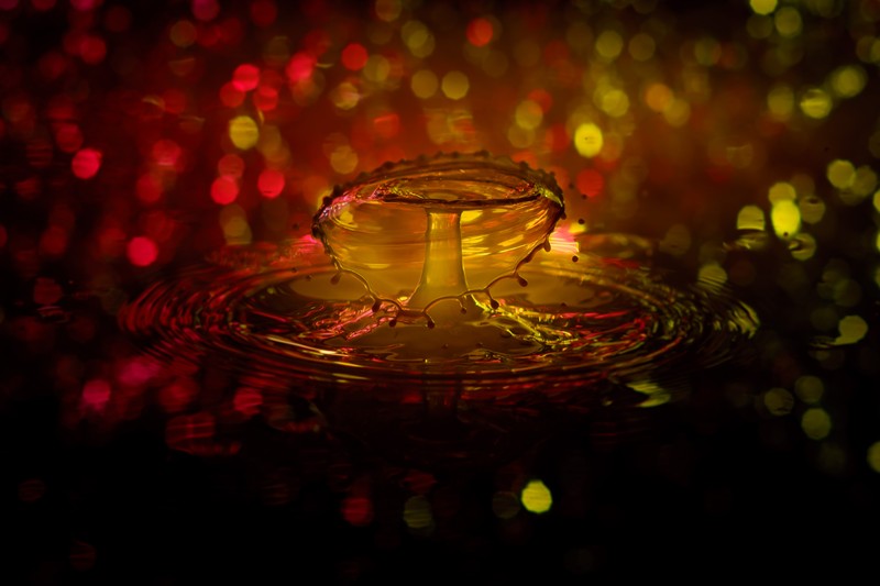 A close up of a tea cup on a plate with a candle (water, red, light, yellow, orange)