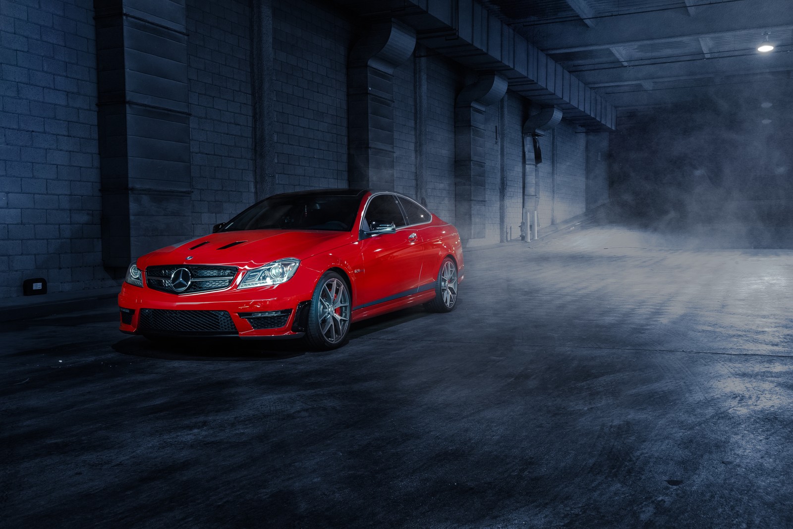 Un primer plano de un coche mercedes rojo en una habitación oscura (coche, llanta, rueda, mercedes amg, mercedes benz clase c)