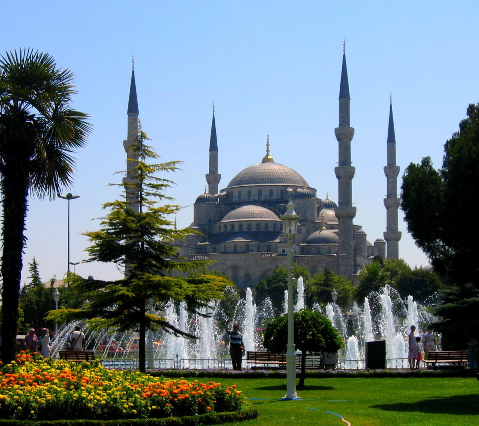 Uma vista de um grande edifício com uma fonte na frente (haram, kaaba, masjid, mesquita, alcorão)