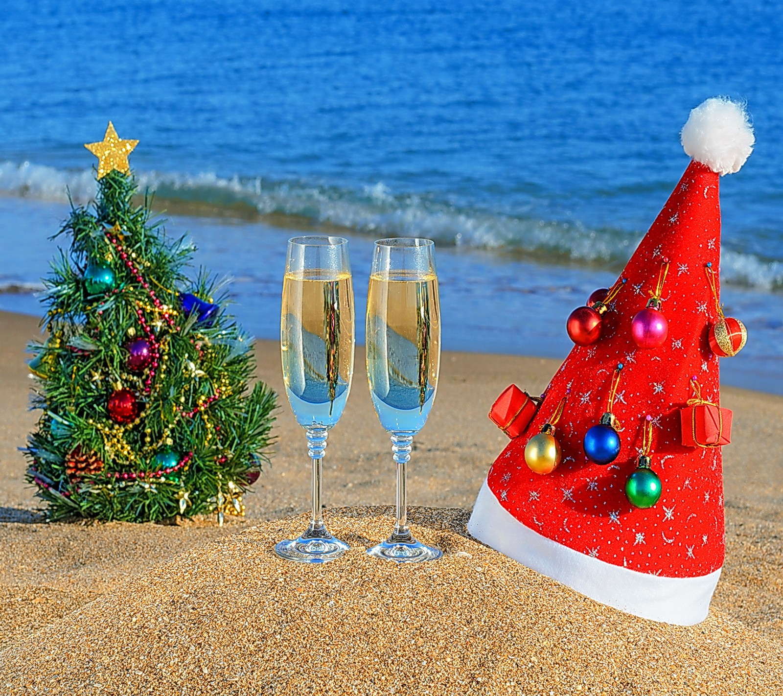 Há duas taças de champanhe e uma árvore de natal na praia (praia, feliz, novo, ano)