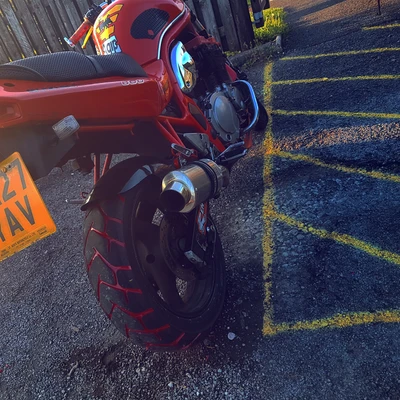 Moto Ducati avec des accents rouges garée dans le parking d'une salle de sport