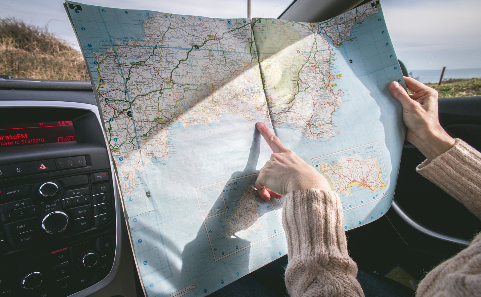 Someone is holding a map in their hand while driving a car (tech, globe, street, world map, travel)