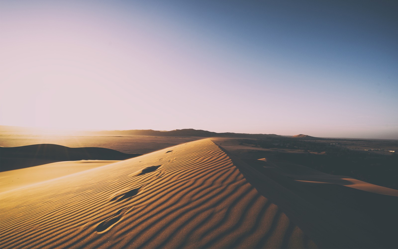 Una vista de un desierto con huellas en la arena. (erg, duna, dune, arena cantante, desierto)