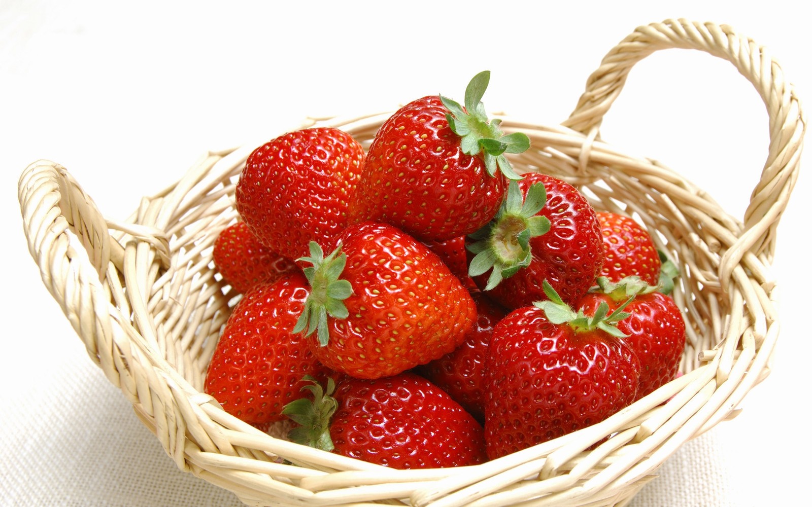 Un panier décoratif de fraises sur une nappe blanche (fraise, fruit, aliments naturels, nourriture, nourriture diététique)