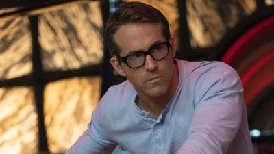 Ryan Reynolds como o icônico personagem de "Free Guy", mostrando um momento contemplativo com óculos estilosos e uma atitude relaxada.