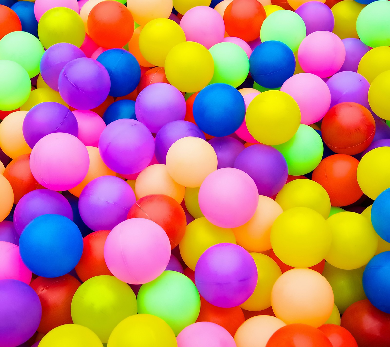 A close up of a bunch of colorful balls in a pile (ball, balloon, color, rainbow)