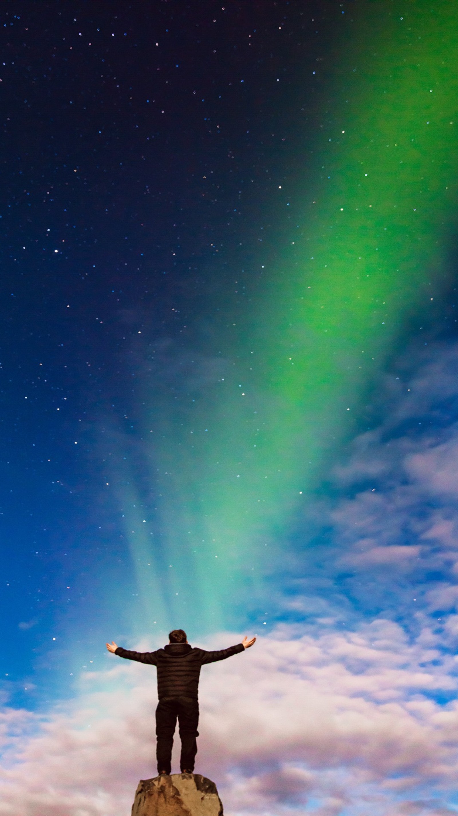 Arafed man standing on a rock with his arms outstretched in the air (appreciation, aurora, beautiful, daylight)