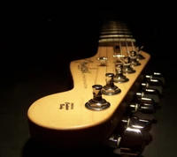 Close-up of a guitar neck showcasing detailed tuning pegs and smooth wood grain against a dark background.