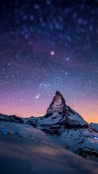 Noche estrellada sobre montañas cubiertas de nieve al atardecer