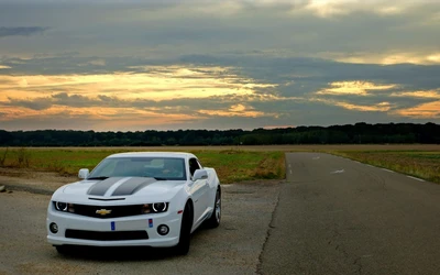 Carro esportivo Chevrolet Camaro branco em uma estrada aberta ao pôr do sol