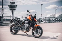 2021 KTM 890 Duke: Auffälliges orangefarbenes Sportmotorrad vor Flughafen-Hintergrund, 4K Hintergrundbild