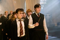 Un grupo de estudiantes de Hogwarts en traje formal, incluyendo a Neville Longbottom y Harry Potter, de pie atentamente en un entorno místico.