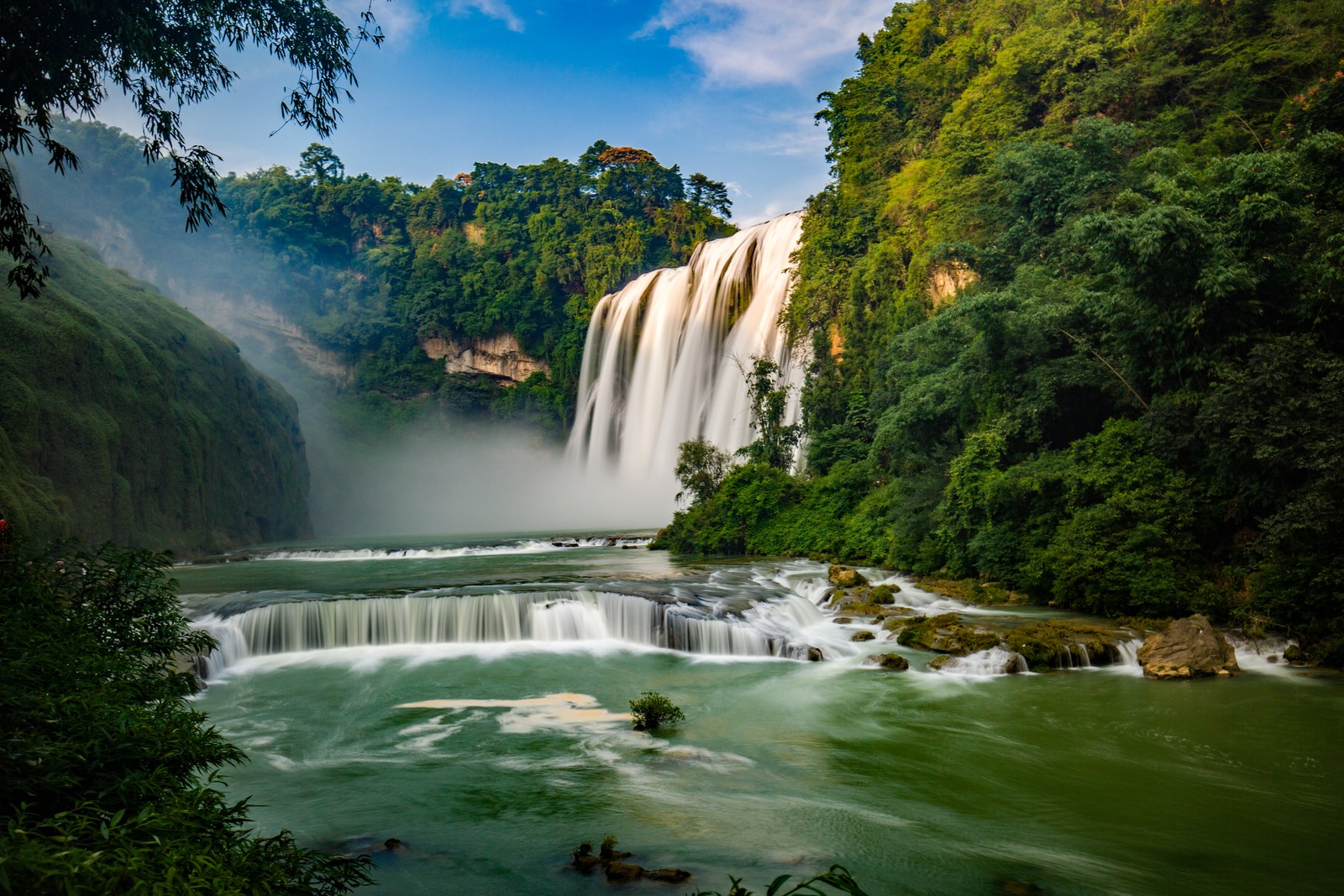 A waterfall in the jungle with a few trees and water (waterfall, body of water, water resources, natural landscape, nature)