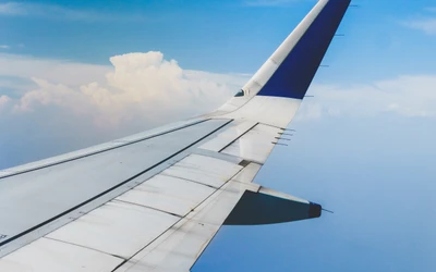 Boeing 777 Wing Against a Clear Sky with Clouds