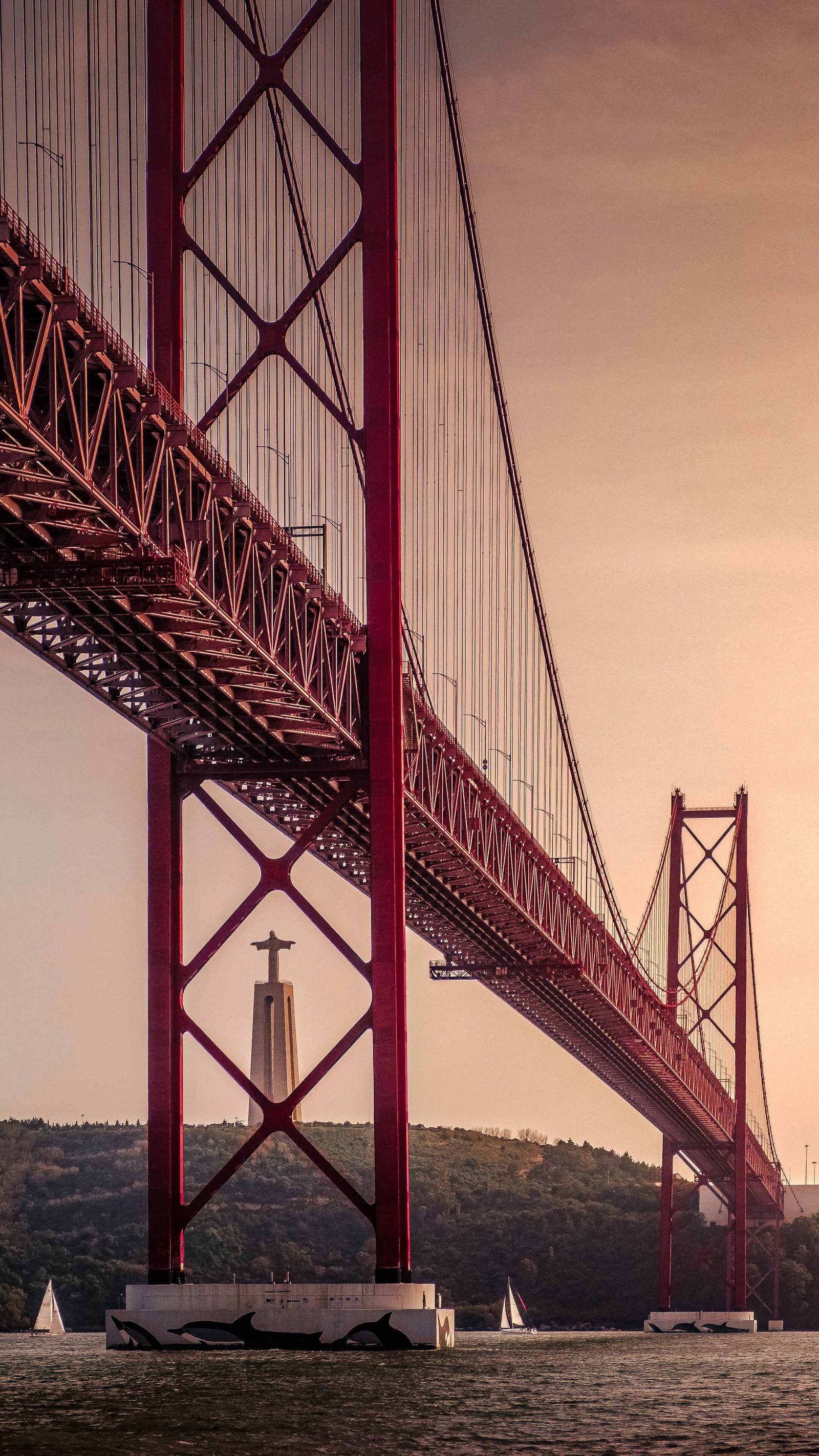 Vista aérea de um farol sob uma ponte com um barco à vela. (ponte, ponte suspensa, ponte golden gate, golden gate bridge, água)