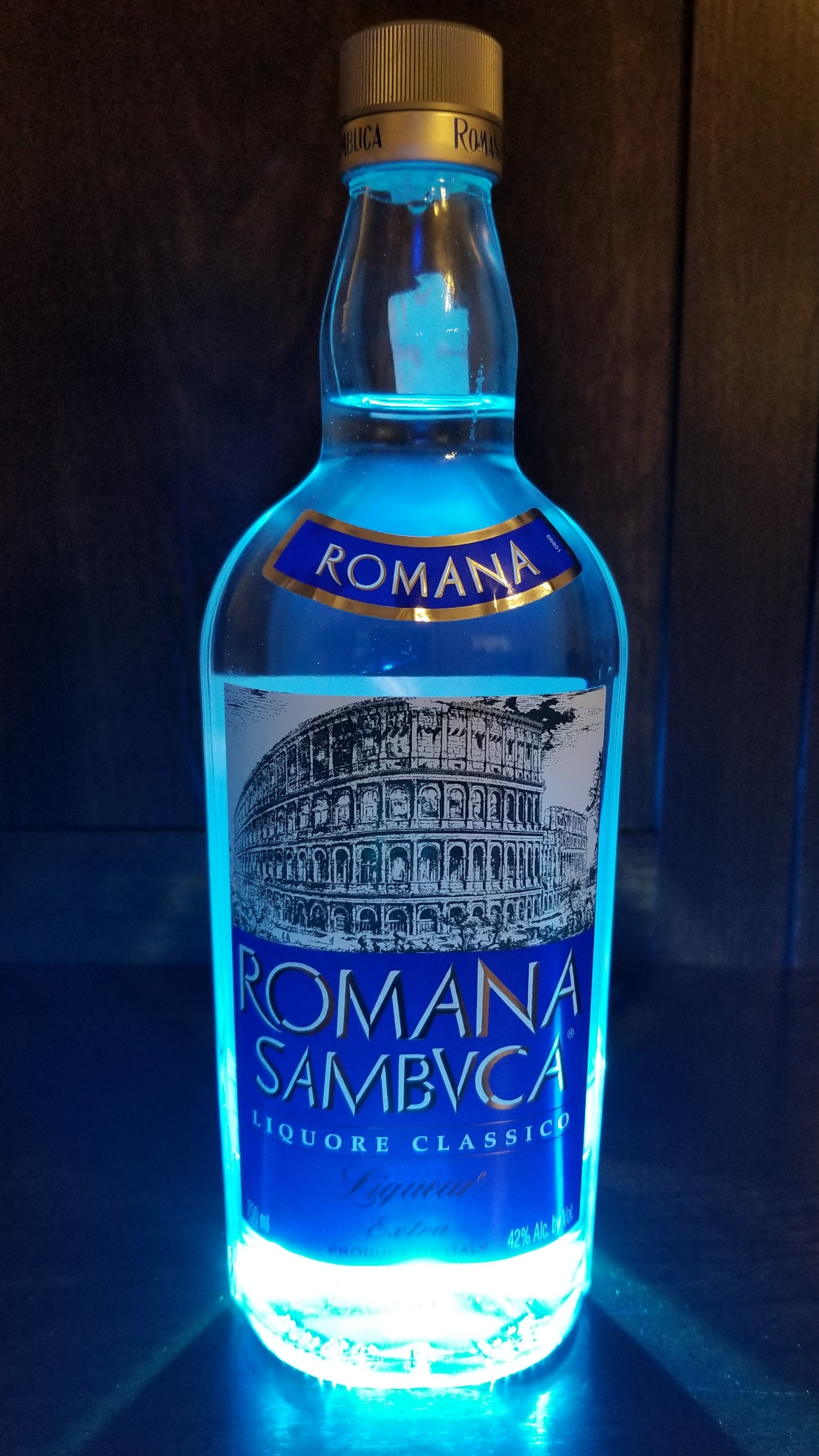 Nahaufnahme einer flasche blauer flüssigkeit auf einem tisch (blau, spirituosen, romana, sambuca, sambvca)