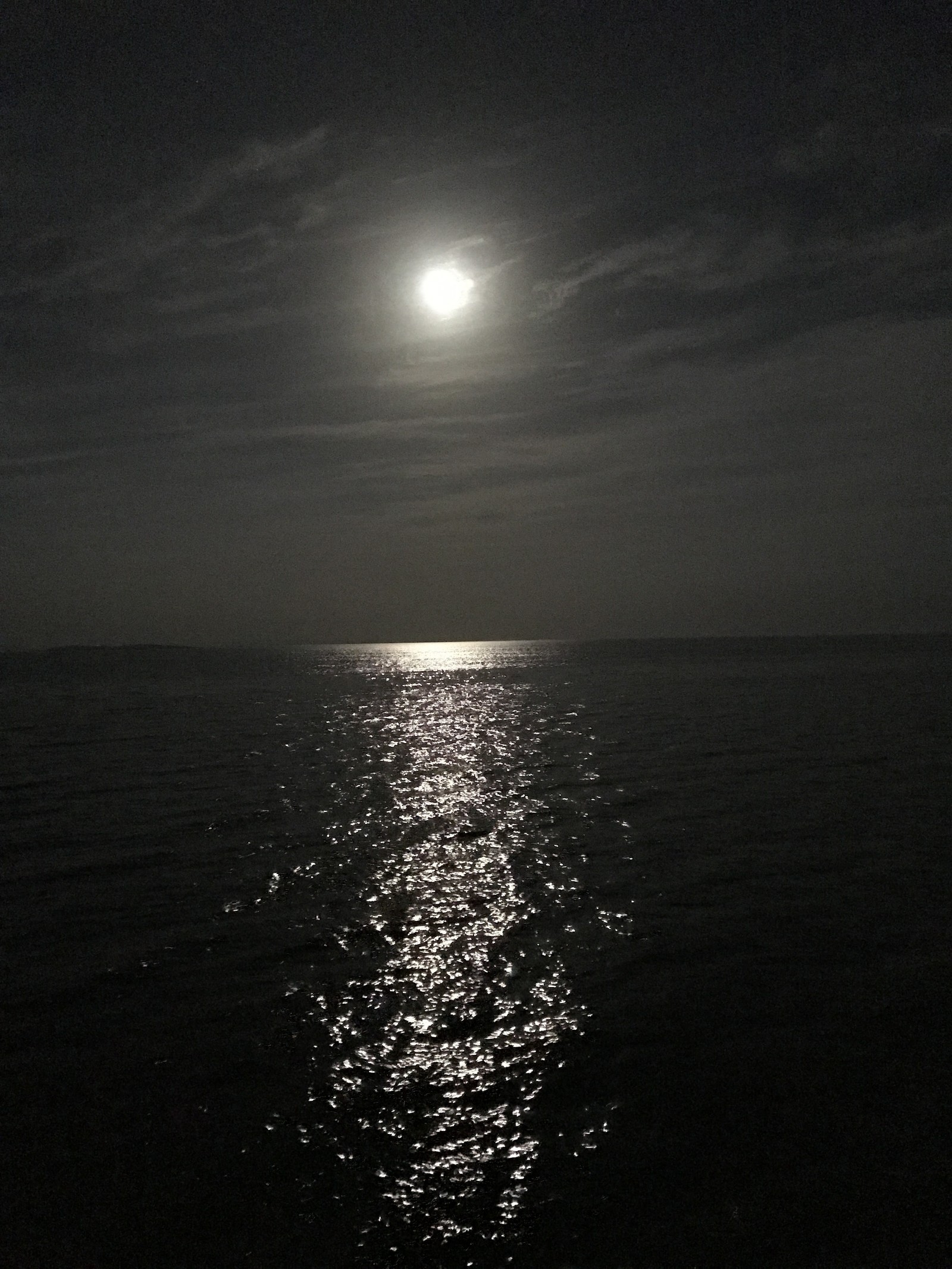 Vista panorámica de una luna llena sobre el océano con un bote a lo lejos (luna, noche)