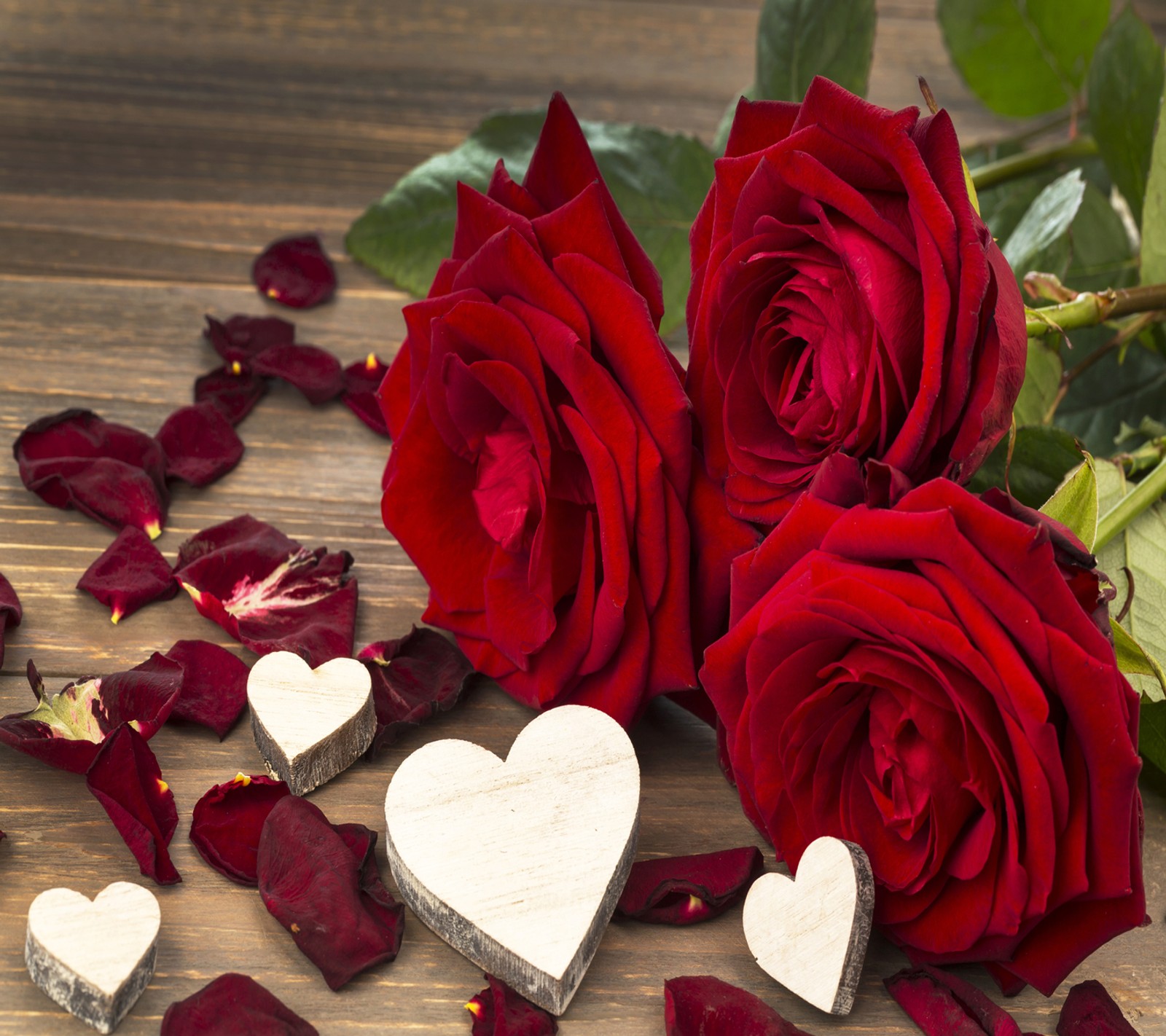 Rosas y corazones sobre una mesa de madera con pétalos esparcidos (rojo, rosas)