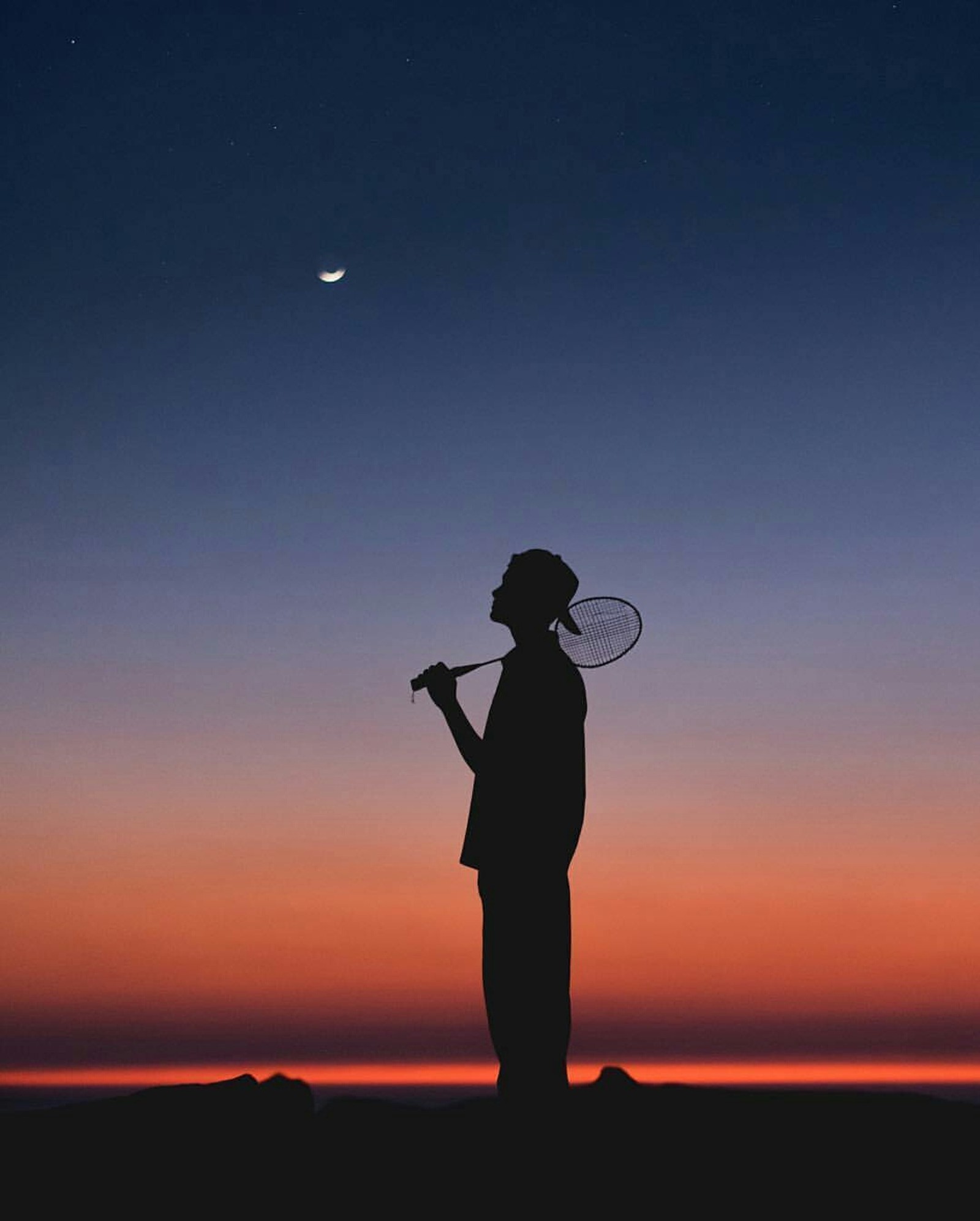 Silhouette of a man holding a tennis racket at sunset (badminton, boy, sky, sunset)