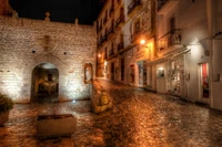 Charming Nighttime Alley in Ibiza with Historic Arch and Illuminated Streets