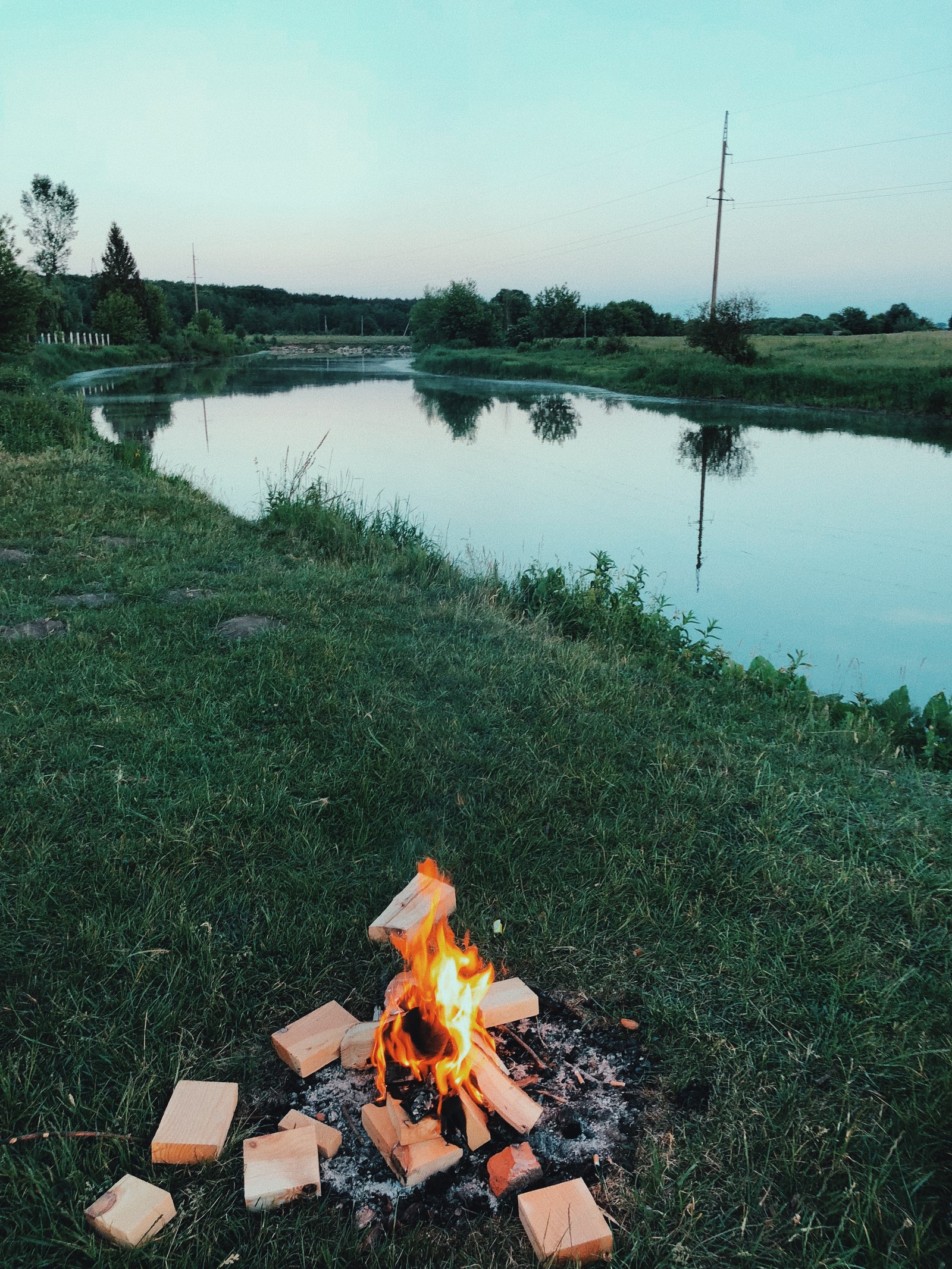 Il y a un feu qui brûle dans l'herbe près de l'eau (réflexion, ressources en eau, eau, zone humide, nature)