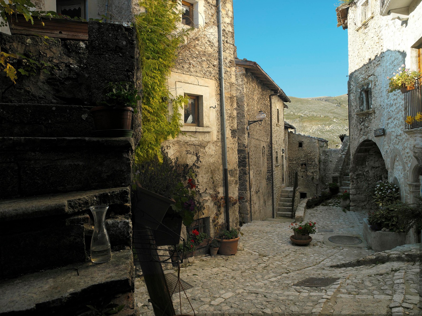 Hay una calle de piedra con una escalera de piedra y un edificio de piedra (habitación, pueblo, calle, ruinas, callejón)