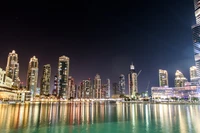 Horizonte iluminado de Dubái reflejado en aguas tranquilas por la noche