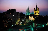 Catedral de Colonia iluminada contra un cielo crepuscular: un impresionante paisaje urbano nocturno.