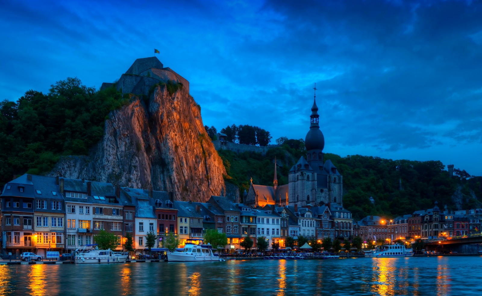 Eine aussicht auf eine stadt mit einem berg im hintergrund (dinant, wahrzeichen, abend, reflexion, stadt)